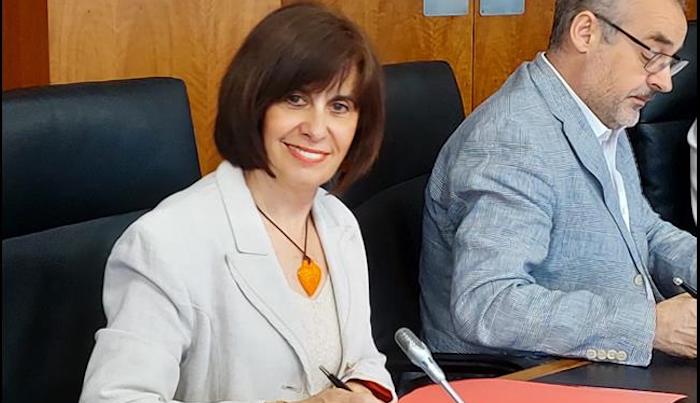 Mujer firmando un documento en una mesa