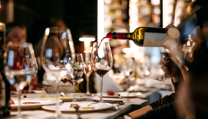 una mesa de restaurante en la que se está sirviendo vino tinto en una copa