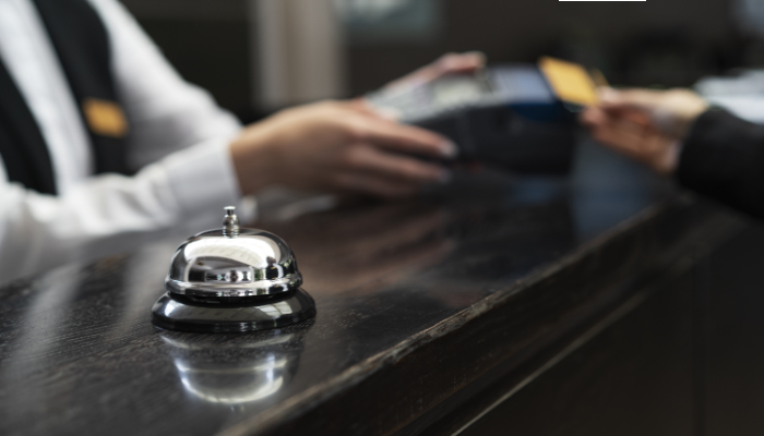 se ve primer plano timbre mostrador de recepción y persona pagando con tarjeta
