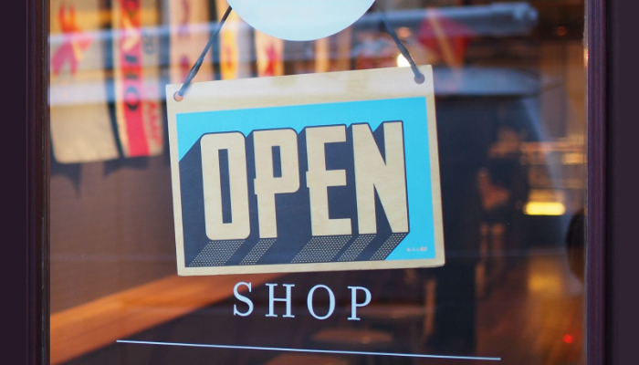 puerta de un comercio con el cartel de abierto