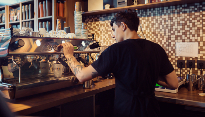 camarero hace un café en la máquina del establecimiento de hostelería