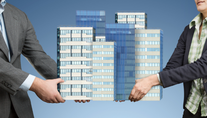 dos personas cogiendo una maqueta de edificios ilustra convenio inmobiliarias