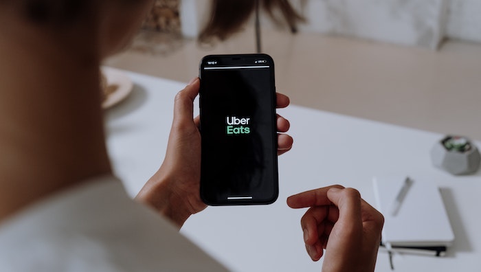 mano de mujer con teléfono móvil con logotipo de Uber Eats
